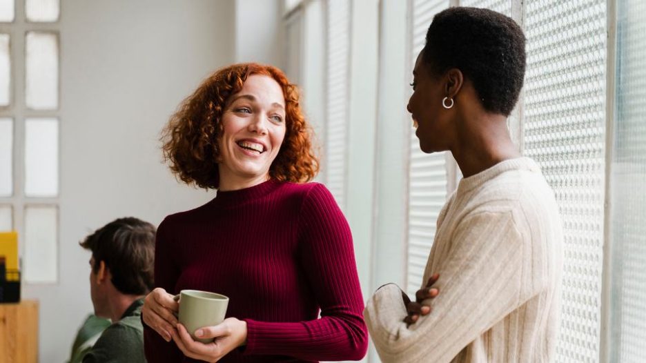 Female colleagues talking and laughing in business space