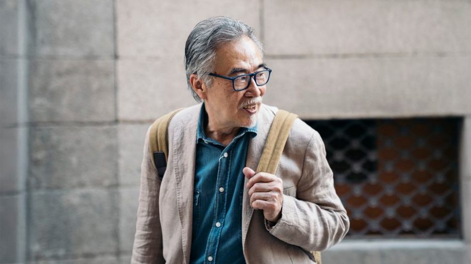 man smiling and looking over his shoulder as he walks through town