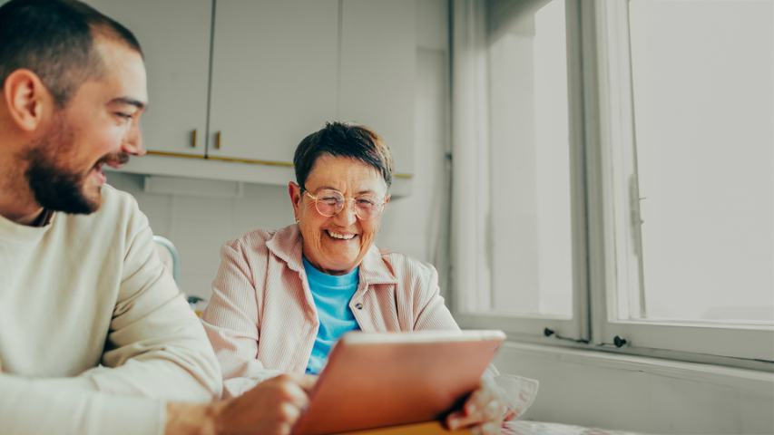 mature woman with tablet helped by young man