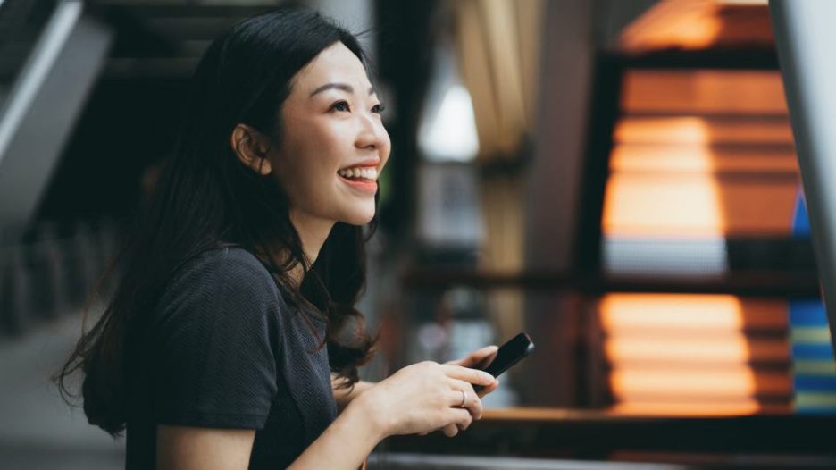 Female holding phone while thinking and smiling