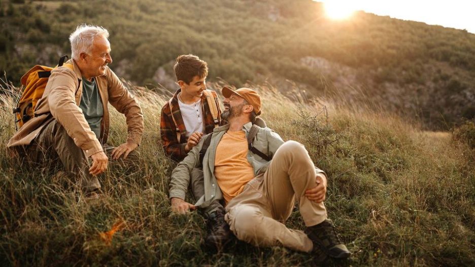 Grandfather, father and son are enjoying a relaxing walk in nature at the end of the day