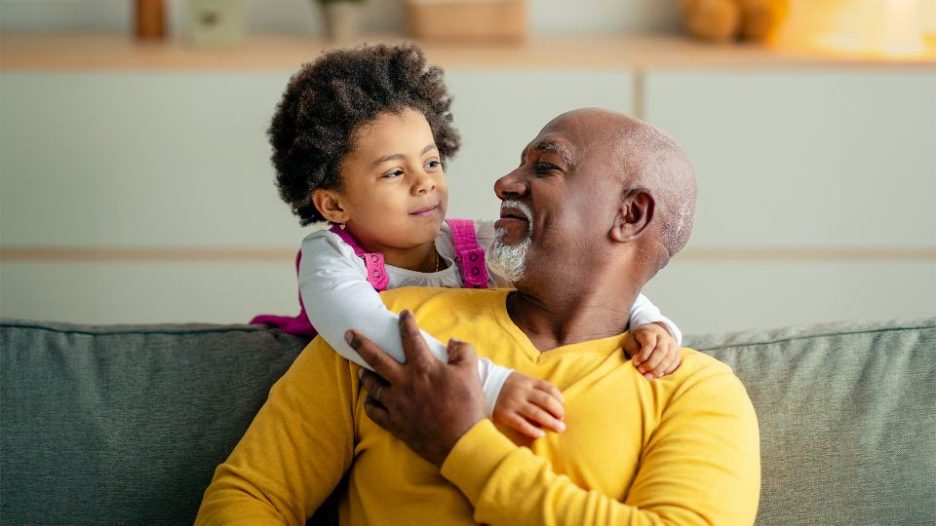 young girl hugging her grandad on the sofa